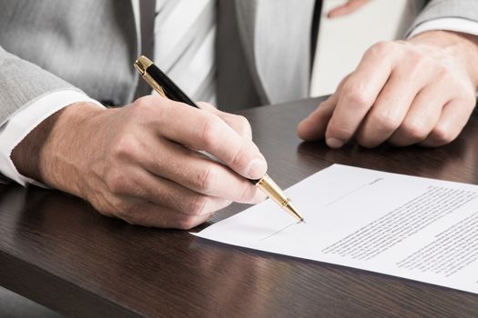 Business man signing a contract with shallow focus on pen and date