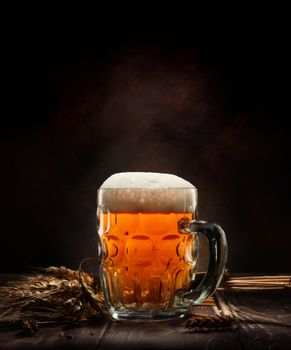 Beer in mug and wheet on wooden table and black background