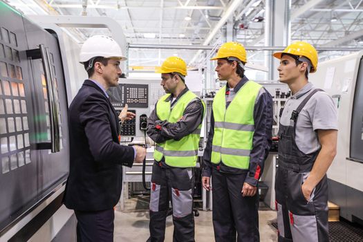 Manager and workers at plant near CNC machines