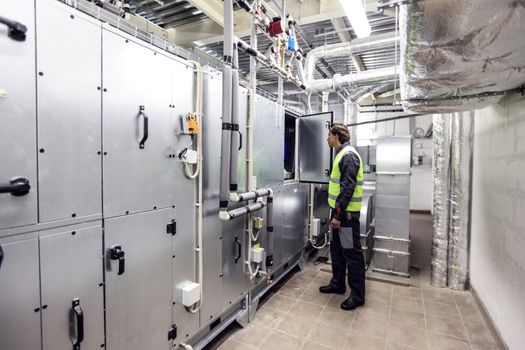 Worker in electrical switchgear room of CNC plant