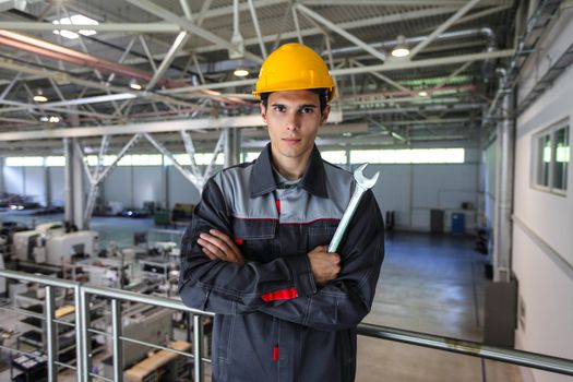 Portrait of young worker with wrench at CNC factory