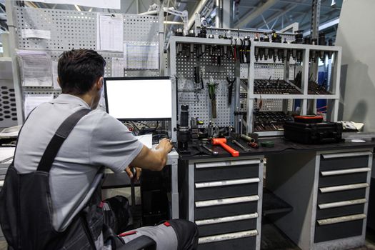 Worker at workplace with computer and tools at CNC factory