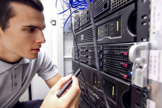 Young engeneer man in network server room checking rack devices