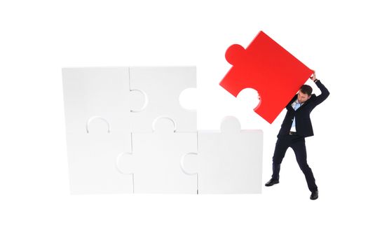 Business man pushing the final piece of puzzle isolated on white