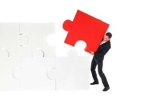 Business man pushing the final piece of puzzle isolated on white