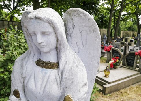 A sculpture of a sad angel walking around the graves of great people.