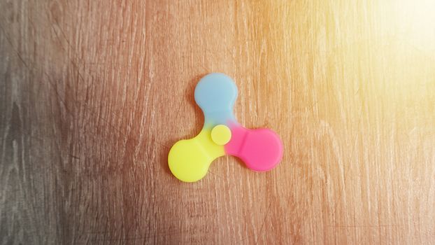Playing with the colorful Fidget Spinner. Toy spinner in hand.Sun effect.