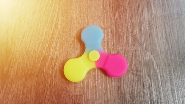 Playing with the colorful Fidget Spinner. Toy spinner in hand.Sun effect.
