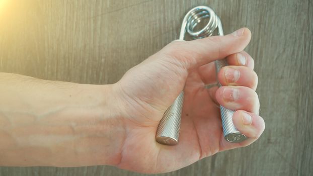 hand expander in the hand of a young athlete. sun effect.