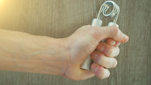 hand expander in the hand of a young athlete. sun effect.