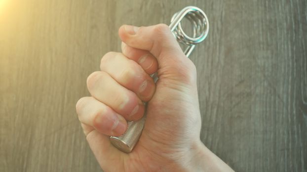 hand expander in the hand of a young athlete. sun effect.