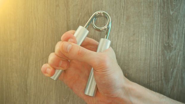 hand expander in the hand of a young athlete. sun effect.