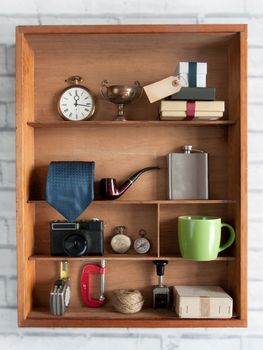 Fathers day gift with a blank label inside a shelving unit with various objects including tools, camera and coffee cup