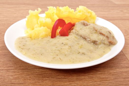 Seitan with dill sauce and potatoes on a wooden table