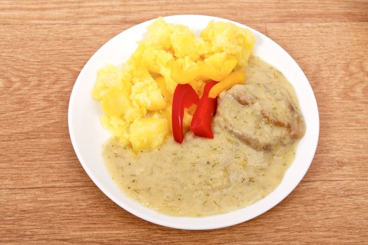 Seitan with dill sauce and potatoes on a wooden table