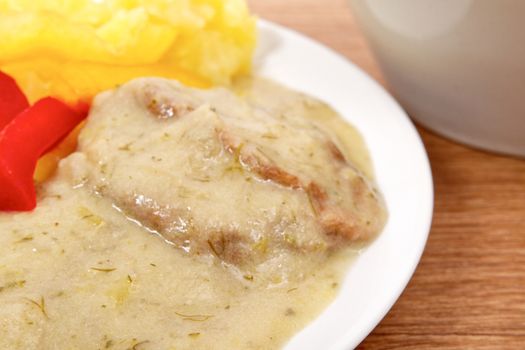 Seitan with dill sauce and potatoes on a wooden table