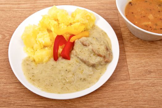 Seitan with dill sauce and potatoes on a wooden table