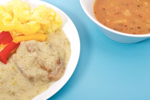 Seitan with dill sauce and potatoes on a blue background