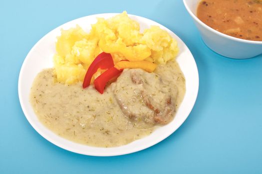 Seitan with dill sauce and potatoes on a blue background