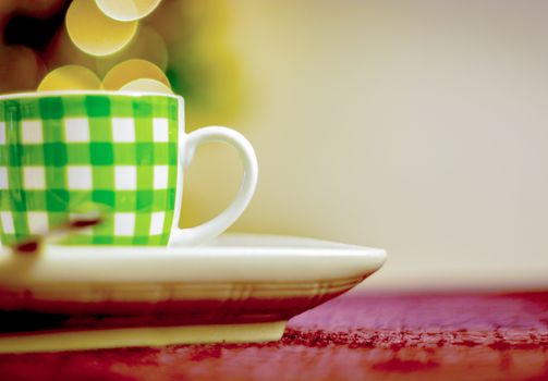 white coffee cup with green stripes with a bokeh effect in the background