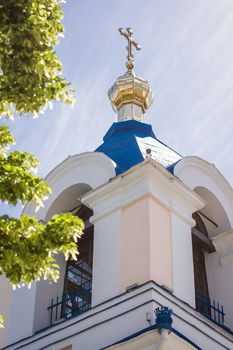 Part of orthodox church roof with cross over blue sky