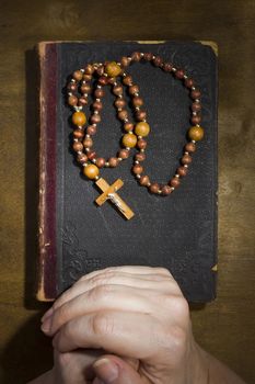 Female hands with rosary and an old book