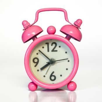 Miniature Vintage Pink Alarm Clock - Minimal Design. Beautiful Pastel Color. Isolated with real shadow reflected on white.