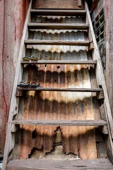 Vintage Old Wooden Ladder with Rusty Corrugated Metal Background. Ancient House in Bangkok, Thailand.