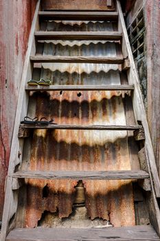 Vintage Old Wooden Ladder with Rusty Corrugated Metal Background. Ancient House in Bangkok, Thailand.