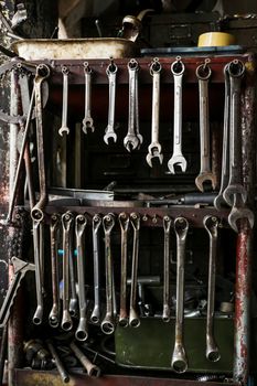 Set of Dirty Wrenches/ Spanners on Wooden Shelf with Different Tools in Garage. Motorbike Repair Shop in  Thailand.