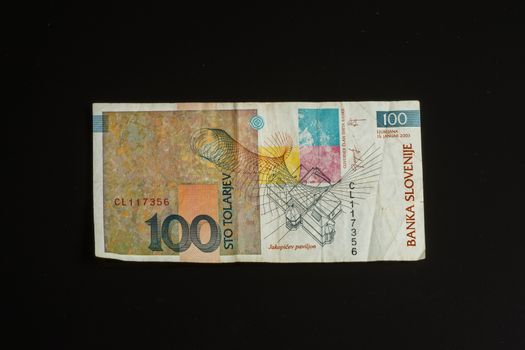 Obsolete 100 tolar bill of Slovenia, became obsolete with introduction of Euro currency, isolated on black background