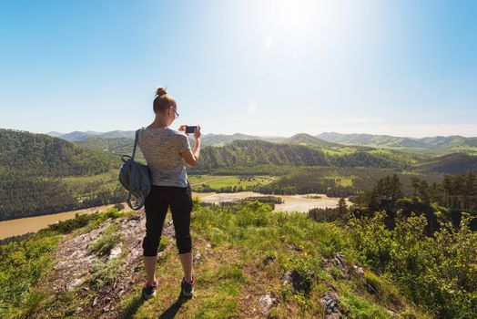 Woman taking photo on mobile phone at the mountain peak.