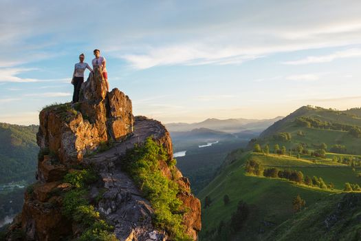 Happy man and woman on top mountain in Altai, sunset light, beauty summer landcape