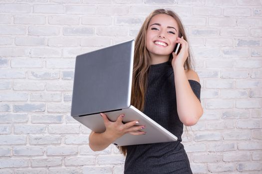 Young beautiful girl model with long hair imitates business lady, office manager or administrator with notebook and telephone