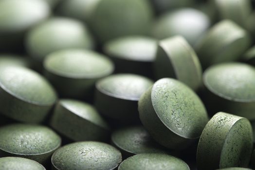 Blue green algae. Close up of natural organic spirulina tablets with focus at the foreground and blur effect