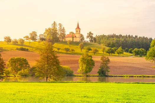 Small church in the middle of lush green spring landscape on sunny day. St. Peter and Pauls church at Bysicky near Lazne Belohrad, Czech Republic.