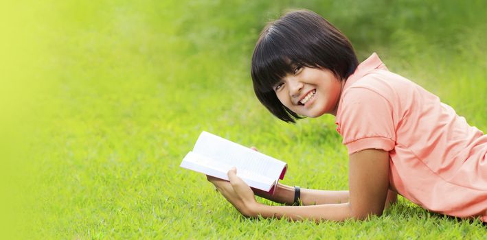 Asian girl reading a book in a park