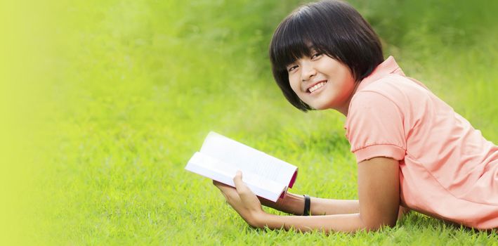 Asian girl reading a book in a park