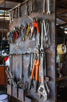 Old tools hanging on metal wall in workshop