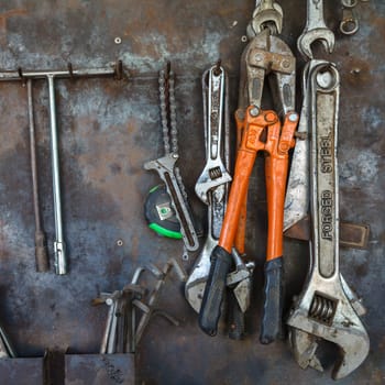 Old tools hanging on metal wall in workshop