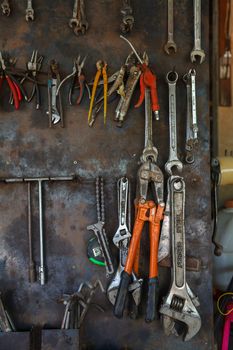 Old tools hanging on metal wall in workshop