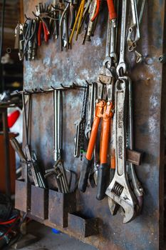 Old tools hanging on metal wall in workshop