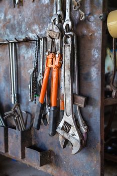 Old tools hanging on metal wall in workshop