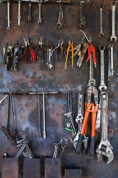 Old tools hanging on metal wall in workshop