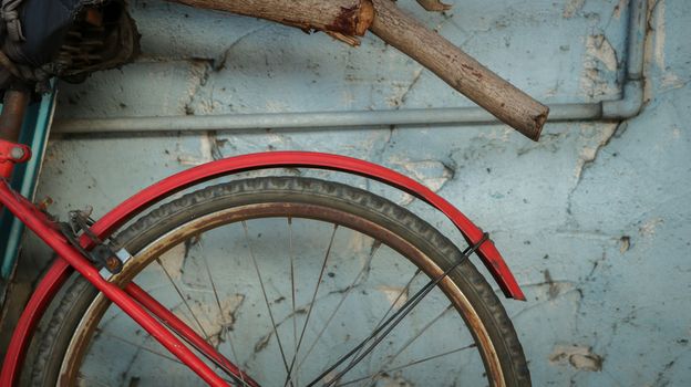 Vintage Old Red Bike on Rough Painted Blue Wall with Rustic Logs/ Dry Tree Branches - Abandoned Garden/ Junkyard. Countryside Thailand.