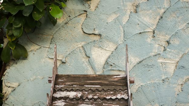 Wooden Roof Pattern with Peeling White Paint on Rough Painted Teal Wall - Green Leaves from the Garden - Miniature Wood Temple/ Spirit House in front of Local Home. Rural Thailand.