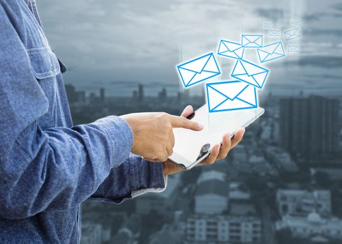 Businessman using digital tablet with modern building and sending e-mails from tablet