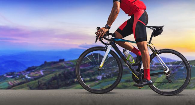 Man on a bicycle on a road between the beautiful mountains