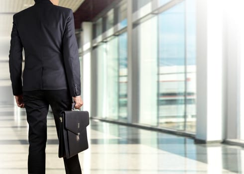 Businessman holding a briefcase in a modern office