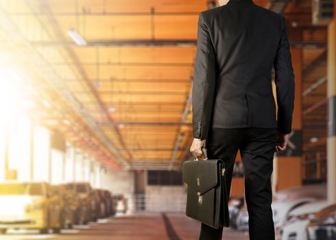 Businessman holding a briefcase in a parking lot on modern office